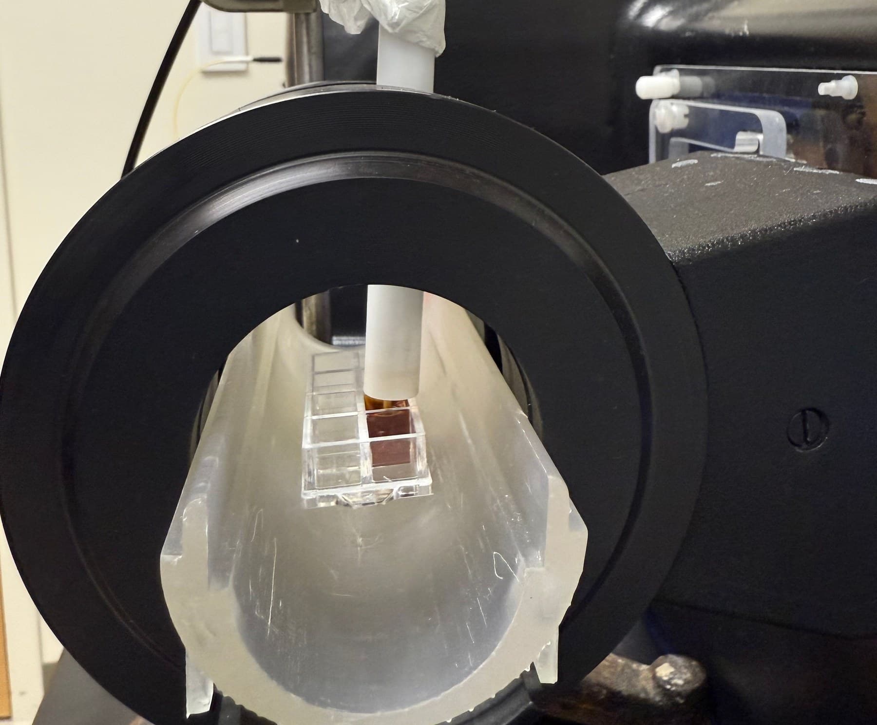 Looking directly into the AMF applicator's coil bore at a nanoparticle sample vial and fiber optic temperature probe positioned between the coils.