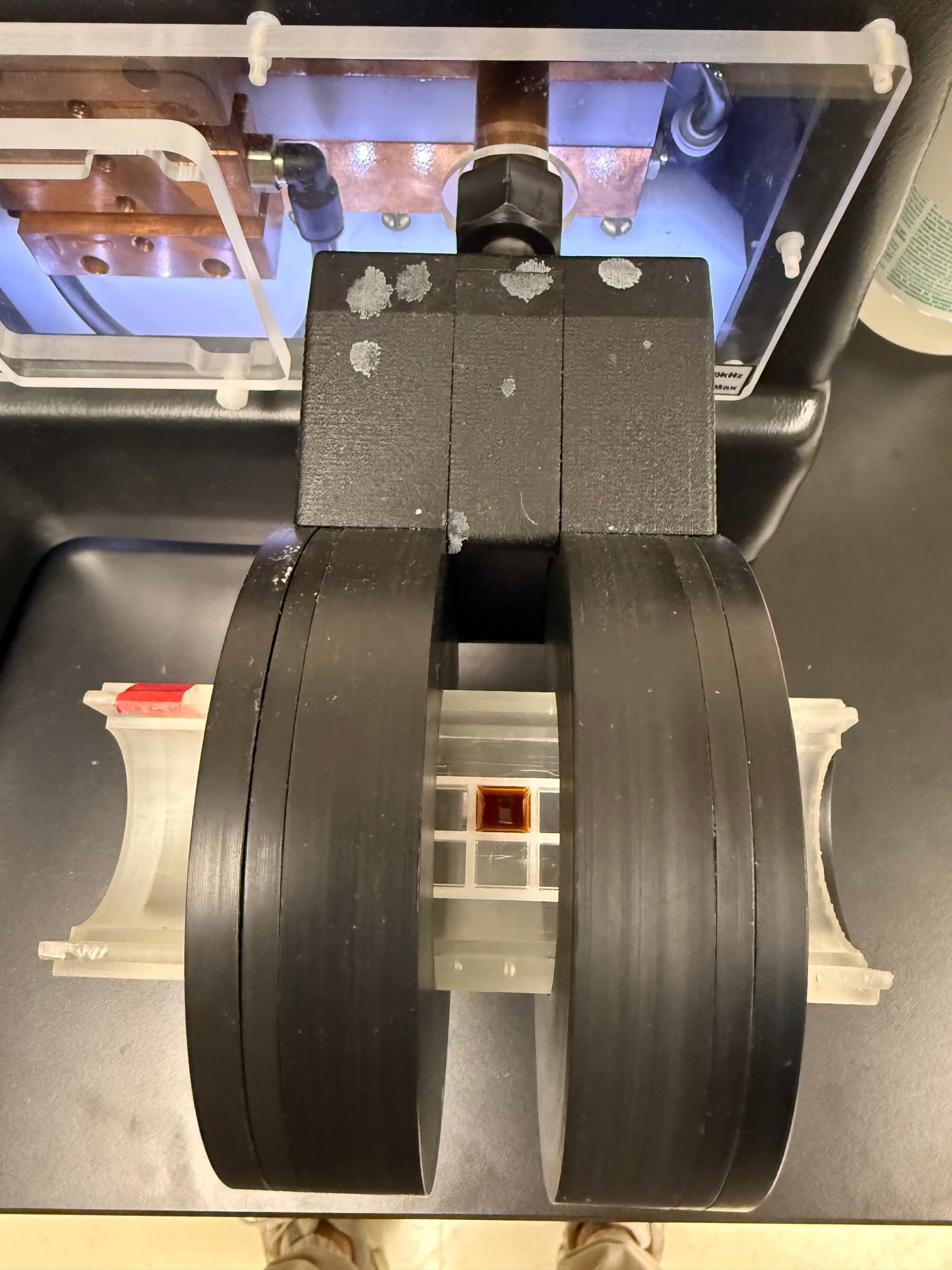 Close-up of a nanoparticle sample vial seated in its 3D-printed holder between the AMF applicator's coils.